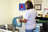 A student assistant in the Library�s Technical Services area staples a musical score into a new binder so that music students can make greater use of it.