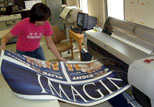 A student employee prints banners on scrim in Copy & Design Services