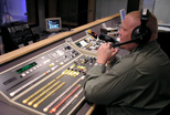 A staff member in the Teleproductions control room prepares to direct an in-studio production.