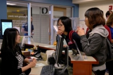 Library staff helping students at Performing Arts Library desk.