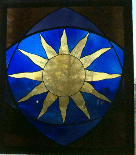 Stained glass window with a yellow sun surround by blue glass.