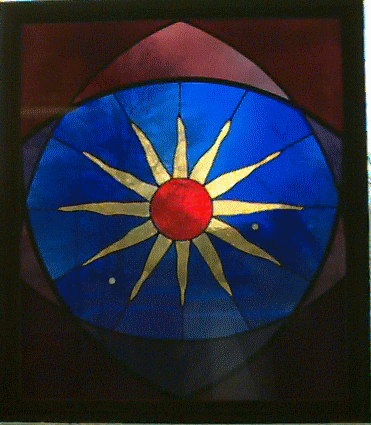 Stained glass window of a yellow sun with a red center, surrounded by blue glass.