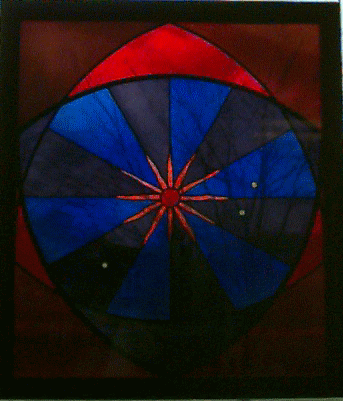 Stained glass window of a red sun surrounded by blue and red glass.