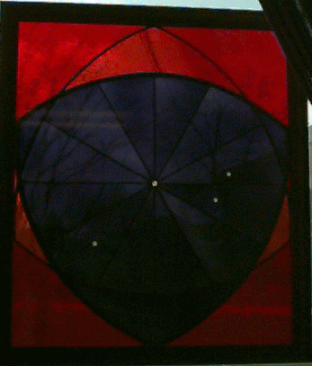 Stained glass window of a dark shape surrounded by red glass.